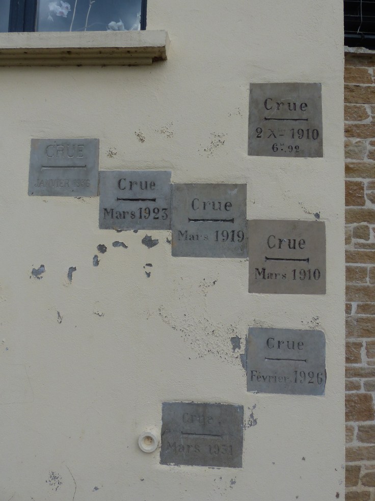 Flood markers on the wall of a house beside the river